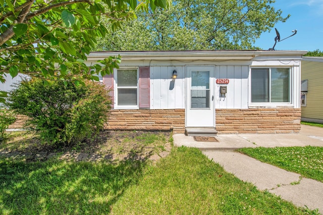 25294 Wiseman St, Roseville, MI 48066 - view of front facade with board and batten siding, stone siding, and a front yard