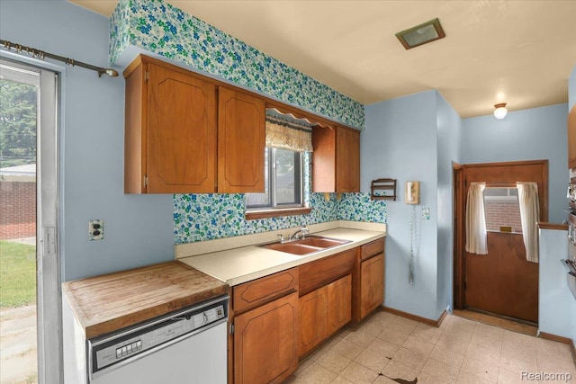 4663 Marian Ave, Warren, MI 48092 - kitchen with white dishwasher, light countertops, plenty of natural light, brown cabinetry, and wallpapered walls
