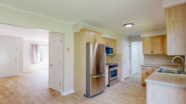7106 Partridge Dr, Flushing, MI 48433 - kitchen with appliances with stainless steel finishes, light brown cabinetry, light countertops, and light wood finished floors