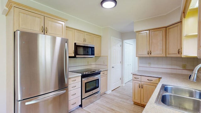 7106 Partridge Dr, Flushing, MI 48433 - kitchen with appliances with stainless steel finishes, light brown cabinets, light countertops, tasteful backsplash, and light wood-style flooring