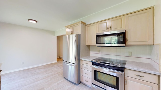 7106 Partridge Dr, Flushing, MI 48433 - kitchen featuring appliances with stainless steel finishes, cream cabinets, decorative backsplash, and light wood finished floors