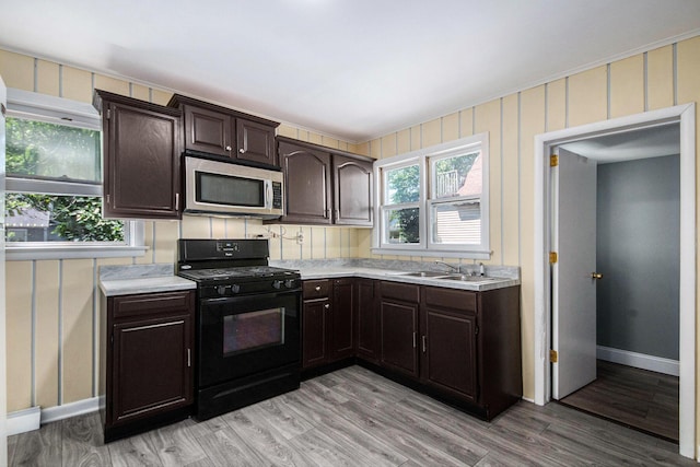814 12th St NW, Grand Rapids, MI 49504 - kitchen with stainless steel microwave, black gas range oven, light countertops, and dark brown cabinetry