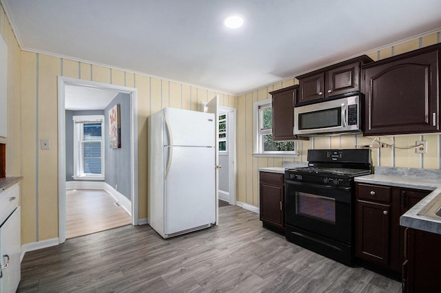 814 12th St NW, Grand Rapids, MI 49504 - kitchen featuring freestanding refrigerator, black gas stove, stainless steel microwave, dark brown cabinetry, and light wood-style flooring