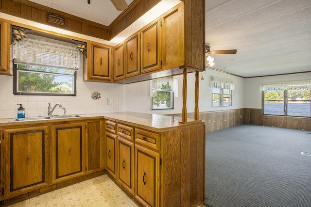12963 E Englewright Dr, Sand Lake, MI 49343 - kitchen with a ceiling fan, brown cabinetry, wainscoting, light countertops, and wooden walls