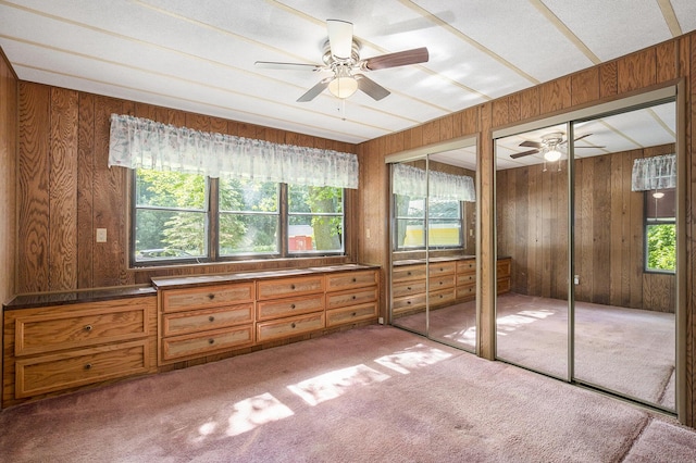 12963 E Englewright Dr, Sand Lake, MI 49343 - unfurnished bedroom featuring two closets, wood walls, carpet flooring, and a ceiling fan