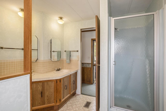 12963 E Englewright Dr, Sand Lake, MI 49343 - bathroom with a stall shower, vanity, tile patterned floors, and decorative backsplash