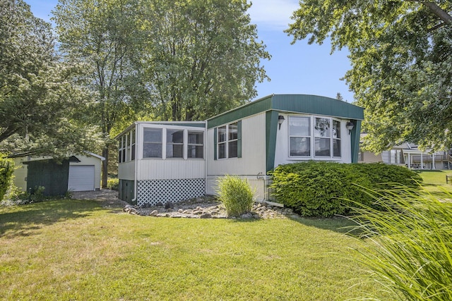 12963 E Englewright Dr, Sand Lake, MI 49343 - view of front facade featuring a front yard, a detached garage, and an outbuilding