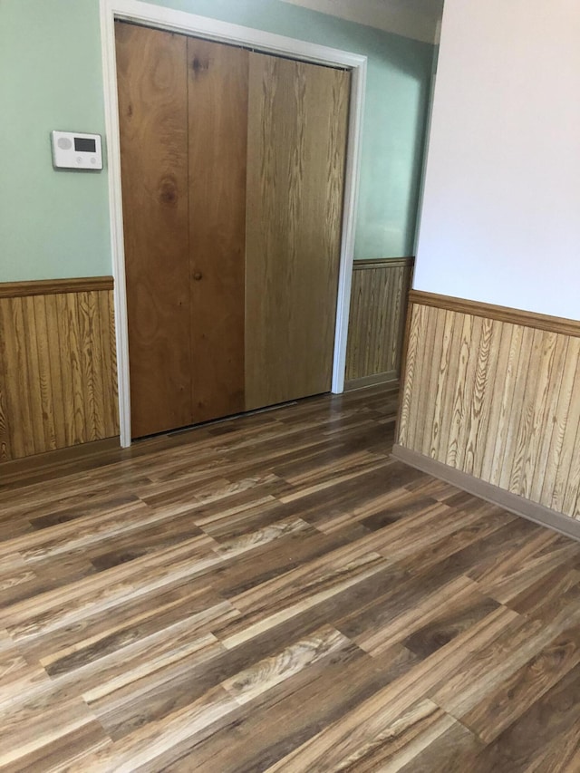 1113 Nichols Rd, Kalamazoo, MI 49006 - unfurnished bedroom featuring wainscoting, wood finished floors, a closet, and wooden walls