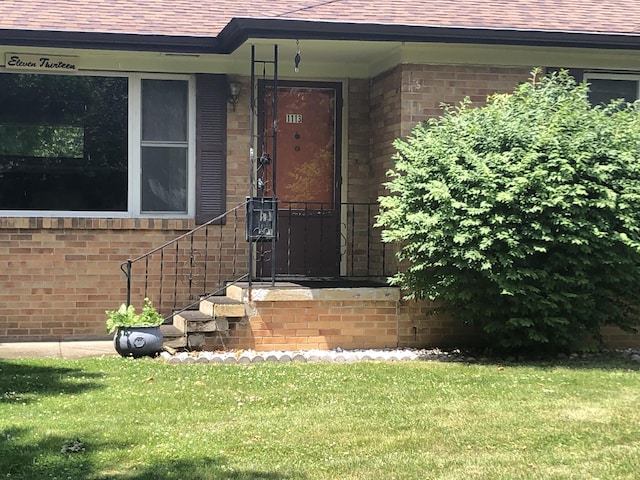 1113 Nichols Rd, Kalamazoo, MI 49006 - doorway to property with brick siding, roof with shingles, and a lawn