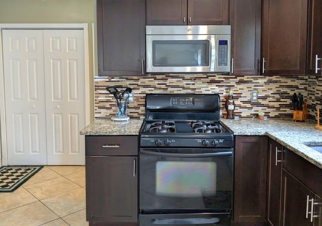6766 Poplar Dr, Ypsilanti, MI 48197 - kitchen with stainless steel microwave, gas stove, dark brown cabinetry, light tile patterned floors, and light stone counters