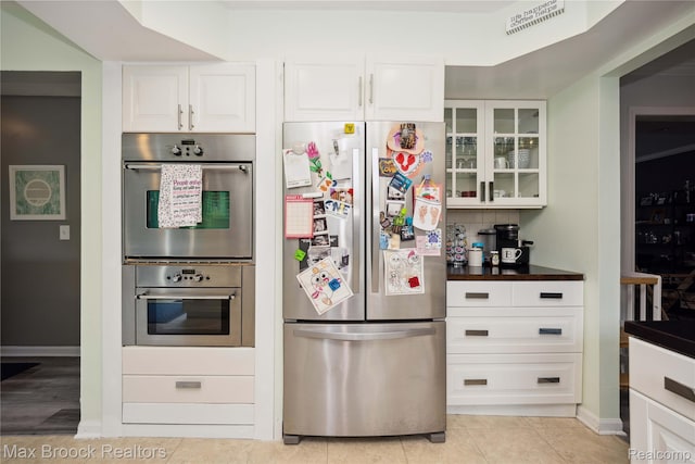 6247 Carpathian Ct, West Bloomfield, MI 48324 - kitchen with stainless steel appliances, dark countertops, glass insert cabinets, white cabinets, and light tile patterned floors