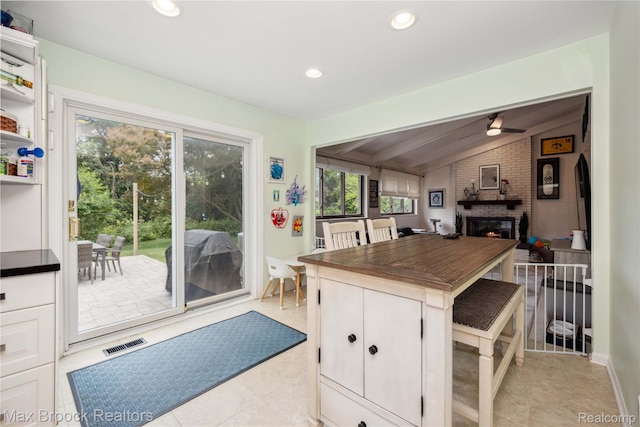 6247 Carpathian Ct, West Bloomfield, MI 48324 - kitchen featuring a brick fireplace, a ceiling fan, dark countertops, light tile patterned floors, and recessed lighting