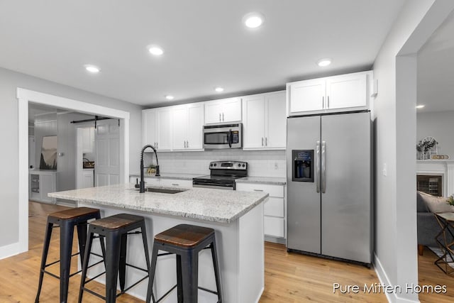 630 Westview Ave NW, Grand Rapids, MI 49504 - kitchen featuring stainless steel appliances, light wood-style floors, white cabinets, and recessed lighting