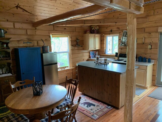 5093 E County Line Rd, Michigan, MI 49411 - kitchen featuring freestanding refrigerator, light wood-type flooring, wood walls, plenty of natural light, and a kitchen island