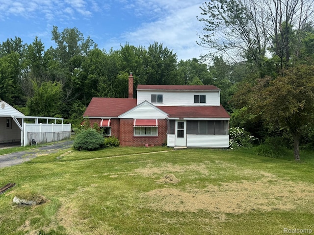 35740 Beverly Rd, Detroit, MI 48174 - view of front of property with a chimney, a sunroom, a front yard, brick siding, and asphalt driveway