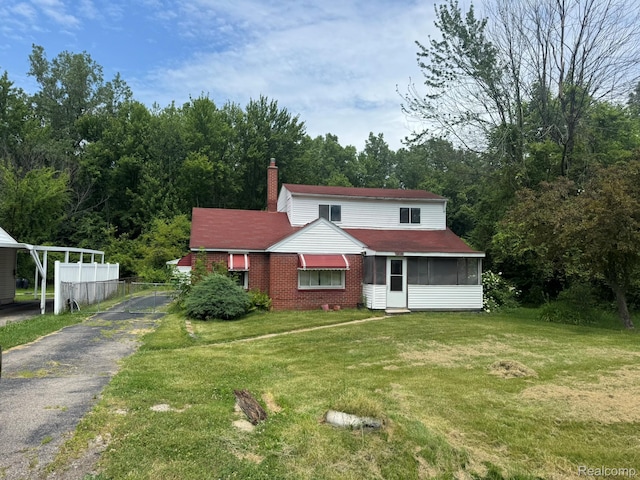 35740 Beverly Rd, Detroit, MI 48174 - view of front of house with driveway, a sunroom, a chimney, a front lawn, and brick siding