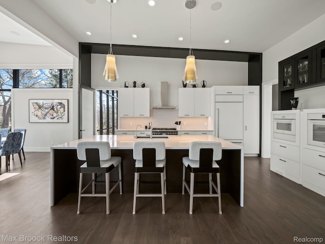 4890 Charing Cross Rd, Bloomfield Hills, MI 48304 - kitchen featuring wall chimney range hood, paneled built in fridge, white oven, light countertops, and a center island with sink