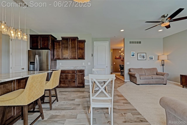 28545 Cottage Ln, New Hudson, MI 48165 - kitchen with stainless steel refrigerator with ice dispenser, ceiling fan, dark brown cabinets, light stone counters, and open floor plan