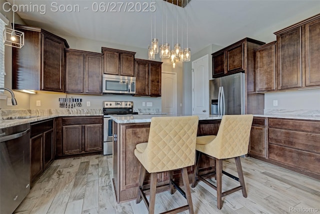 28545 Cottage Ln, New Hudson, MI 48165 - kitchen with stainless steel appliances, dark brown cabinets, a kitchen island, and light stone counters