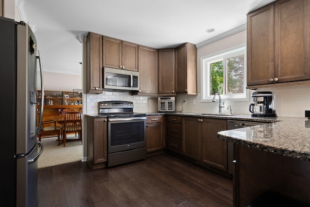 7662 Hidden Ponds Blvd, Brighton, MI 48114 - kitchen featuring appliances with stainless steel finishes, dark wood finished floors, dark stone counters, decorative backsplash, and crown molding