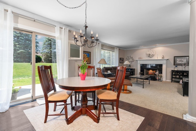 7662 Hidden Ponds Blvd, Brighton, MI 48114 - dining room with a lit fireplace, a chandelier, crown molding, and wood finished floors