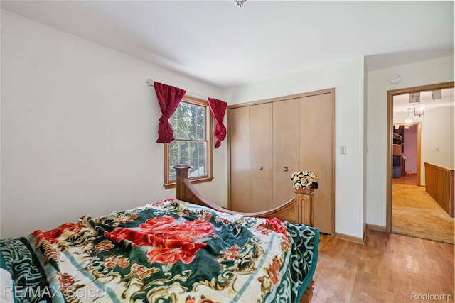 6088 Sierra Pass, Flint, MI 48532 - bedroom with light wood-type flooring, a closet, and a chandelier