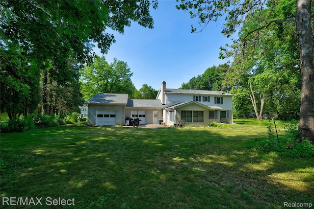 6088 Sierra Pass, Flint, MI 48532 - rear view of house with a chimney, an attached garage, and a lawn