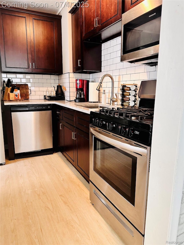 23360 Battelle Ave, Hazel Park, MI 48030 - kitchen with appliances with stainless steel finishes, light countertops, decorative backsplash, light wood-style floors, and dark brown cabinetry