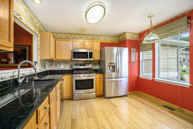 1721 Quail Run Dr, Kalamazoo, MI 49009 - kitchen with appliances with stainless steel finishes, light wood-style floors, decorative backsplash, decorative light fixtures, and dark stone counters