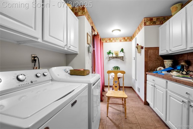 9000 Ferry Rd, Grosse Ile, MI 48138 - washroom featuring separate washer and dryer, cabinet space, and light tile patterned flooring
