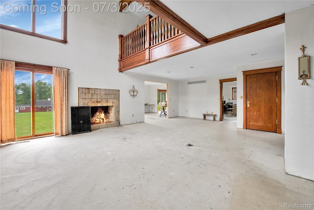 9000 Ferry Rd, Grosse Ile, MI 48138 - unfurnished living room featuring a towering ceiling, unfinished concrete flooring, and a fireplace