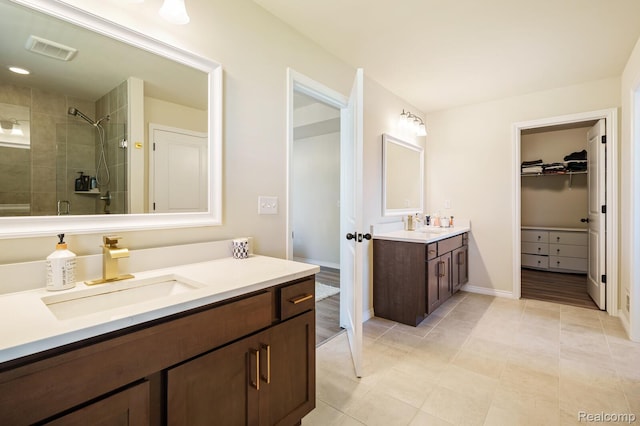 1957 Emerald Ln, Wixom, MI 48393 - full bathroom featuring a tile shower, two vanities, a walk in closet, and tile patterned floors