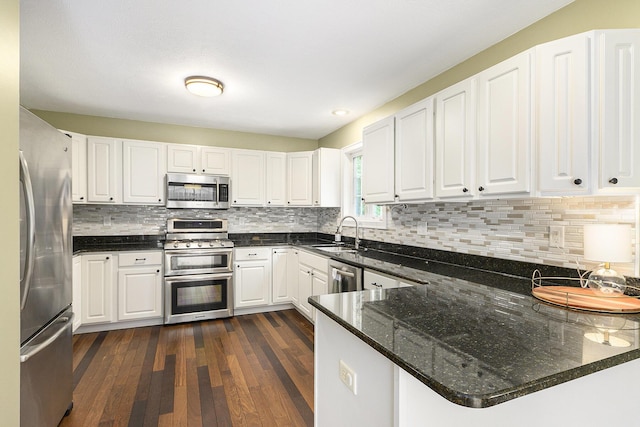 8601 Hathaway Rd, Kalamazoo, MI 49009 - kitchen featuring stainless steel appliances, a peninsula, dark wood-type flooring, white cabinetry, and backsplash
