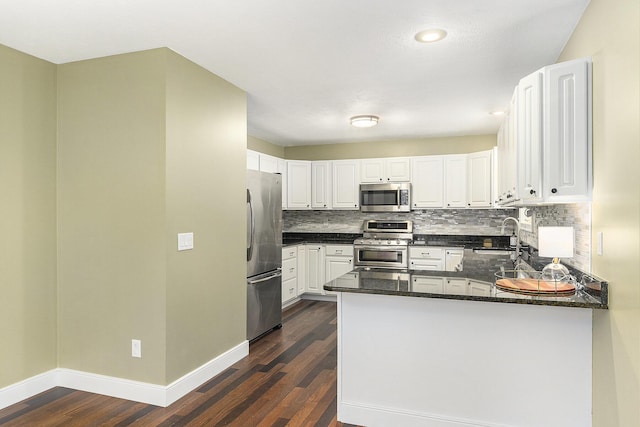 8601 Hathaway Rd, Kalamazoo, MI 49009 - kitchen with appliances with stainless steel finishes, dark wood-type flooring, decorative backsplash, a peninsula, and white cabinetry
