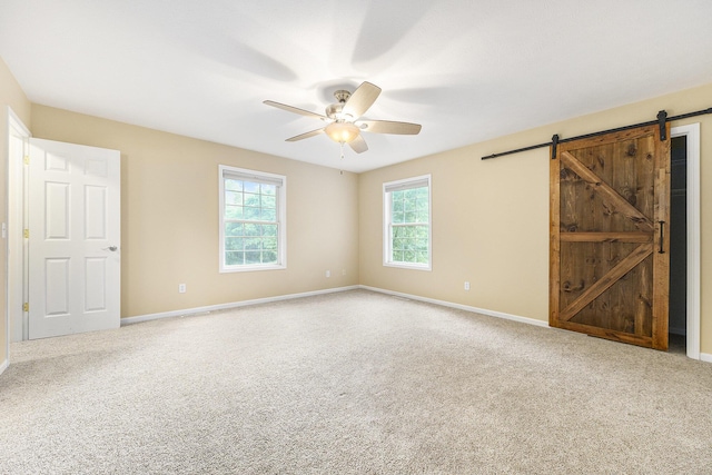 8601 Hathaway Rd, Kalamazoo, MI 49009 - unfurnished bedroom featuring a barn door, carpet floors, and ceiling fan