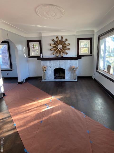 14402 Southfield Rd, Detroit, MI 48223 - unfurnished living room featuring a fireplace, wood finished floors, and arched walkways