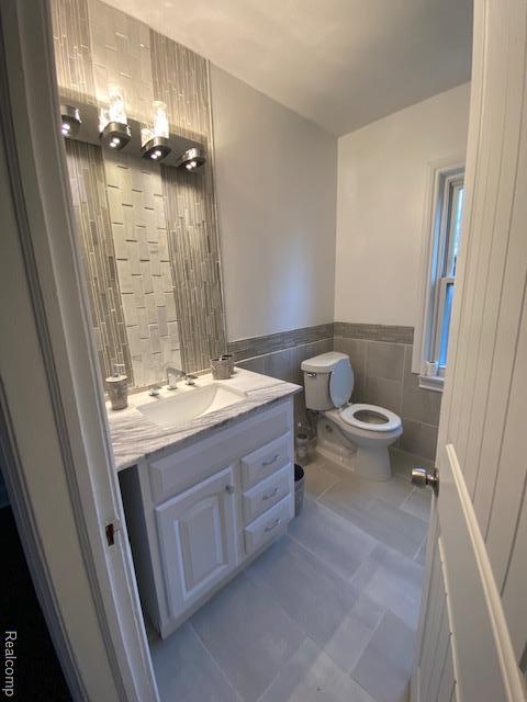 14402 Southfield Rd, Detroit, MI 48223 - bathroom featuring tile walls, vanity, tile patterned floors, and wainscoting