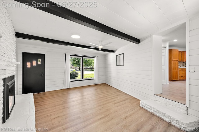 4550 Justine St, Shelby Twp, MI 48317 - unfurnished living room with a ceiling fan, light wood-style flooring, beamed ceiling, a fireplace with raised hearth, and wooden walls