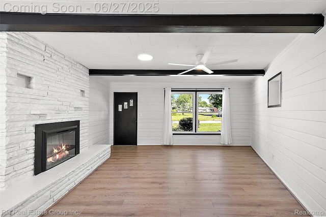 4550 Justine St, Shelby Twp, MI 48317 - unfurnished living room with beam ceiling, a stone fireplace, wood finished floors, ceiling fan, and wooden walls