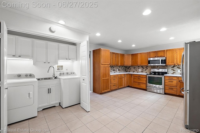 4550 Justine St, Shelby Twp, MI 48317 - kitchen featuring appliances with stainless steel finishes, backsplash, light countertops, light tile patterned flooring, and washer and dryer