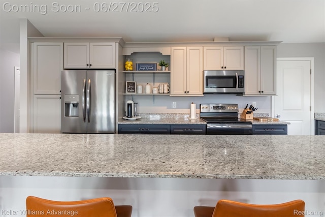 11785 Cardwell St, Dearborn Heights, MI 48150 - kitchen with appliances with stainless steel finishes, a breakfast bar, light stone countertops, and open shelves