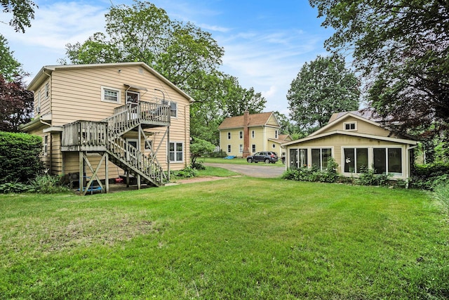 317 E Chart St, Plainwell, MI 49080 - rear view of house with stairway, a sunroom, a yard, and a wooden deck