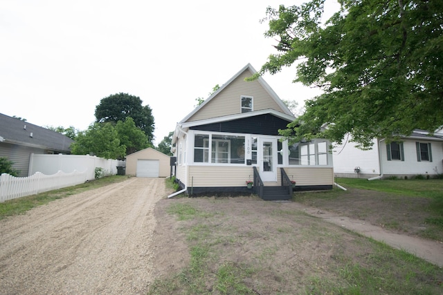 1100 W Laketon Ave, Muskegon, MI 49441 - view of front of home with dirt driveway, an outbuilding, a sunroom, entry steps, and a garage