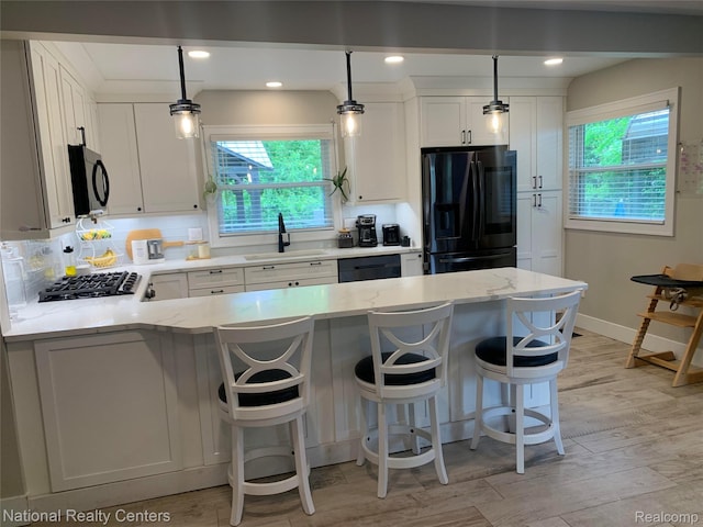 1485 Paramount St, Novi, MI 48377 - kitchen featuring black appliances, plenty of natural light, light stone counters, a peninsula, and recessed lighting