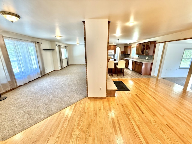 10844 Judd Rd, Willis, MI 48191 - unfurnished living room featuring light wood-style flooring, healthy amount of natural light, and light colored carpet