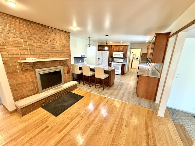 10844 Judd Rd, Willis, MI 48191 - kitchen featuring white appliances, a peninsula, light wood finished floors, a breakfast bar, and brown cabinets