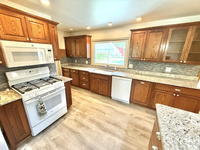 10844 Judd Rd, Willis, MI 48191 - kitchen with white appliances, tasteful backsplash, brown cabinetry, light stone counters, and light wood-type flooring