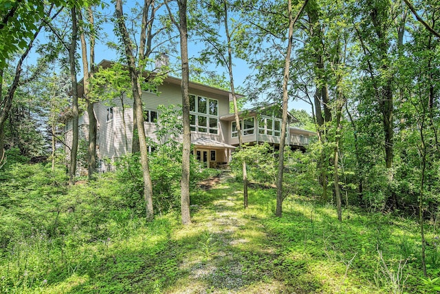 8023 Trail Rdg, Dexter, MI 48130 - back of property featuring a chimney, a deck, and a sunroom