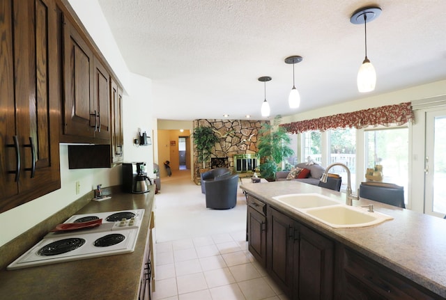 8141 N Elms Rd, Flushing, MI 48433 - kitchen featuring open floor plan, white electric stovetop, a fireplace, dark brown cabinetry, and pendant lighting