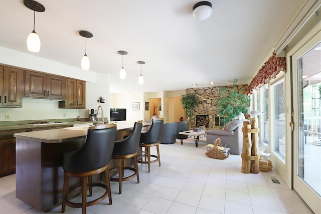 8141 N Elms Rd, Flushing, MI 48433 - kitchen featuring a stone fireplace, electric cooktop, decorative light fixtures, a breakfast bar area, and open floor plan